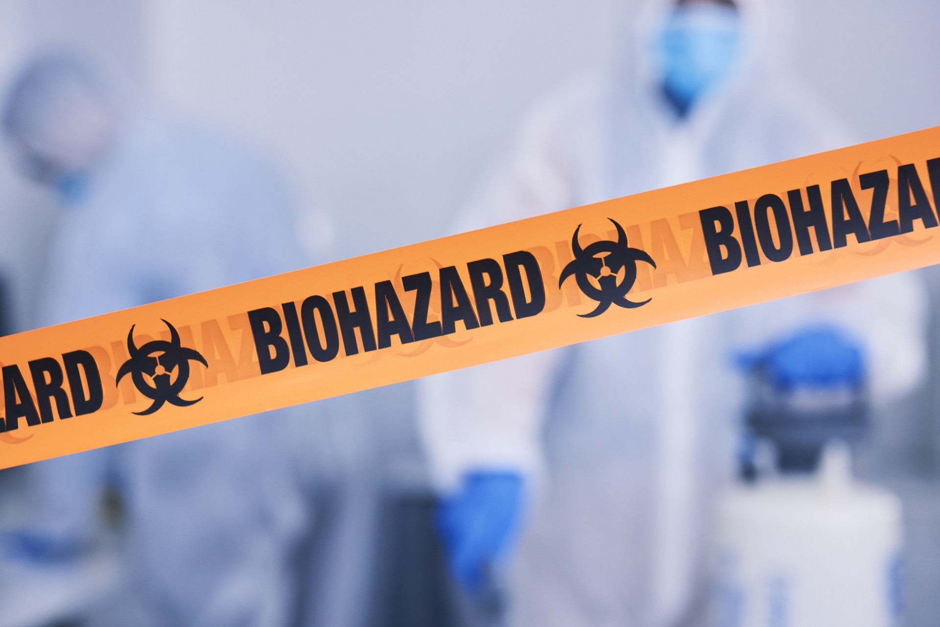 Biohazard, tape and people with caution working with toxic, biology or team disinfect dangerous bacteria for health crisis. Hazard, protection and warning for bio safety or cleaning in hazmat suit